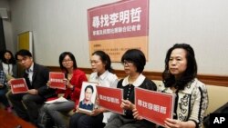 In this photo taken March 24, 2017, Lee Ching-yu, third from right holds up a photo of her missing husband and Taiwanese pro-democracy activist Lee Ming-che during a press conference with other representatives of non-governmental organizations calling for help to find his whereabouts in Taipei, Taiwan. 