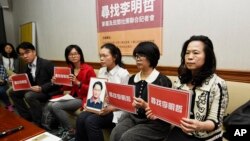 FILE - In this photo taken Friday, March 24, 2017, Lee Ching-yu, third from right holds up a photo of her missing husband and Taiwanese pro-democracy activist Lee Ming-che during a press conference.