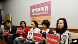 FILE - In this photo taken March 24, 2017, Lee Ching-yu holds a photo of her missing husband and Taiwanese pro-democracy activist Lee Ming-che during a press conference in Taipei, Taiwan.