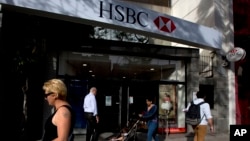 FILE - People walk past an HSBC branch in Buenos Aires, Argentina, Nov. 28, 2014.