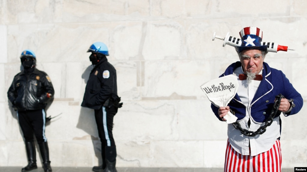 Seorang pria mengenakan kostum berpose di samping polisi di Lincoln Memorial dalam aksi unjuk rasa menentang mandat vaksin di Washington, D.C., pada 23 Januari 2022. (Foto: Reuters/Tom Brenner)