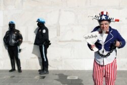 Un hombre disfrazado posa junto a agentes de policía en el Monumento a Lincoln durante la marcha del mandato antivacunas en Washington, D.C., EE. UU., el 23 de enero de 2022.