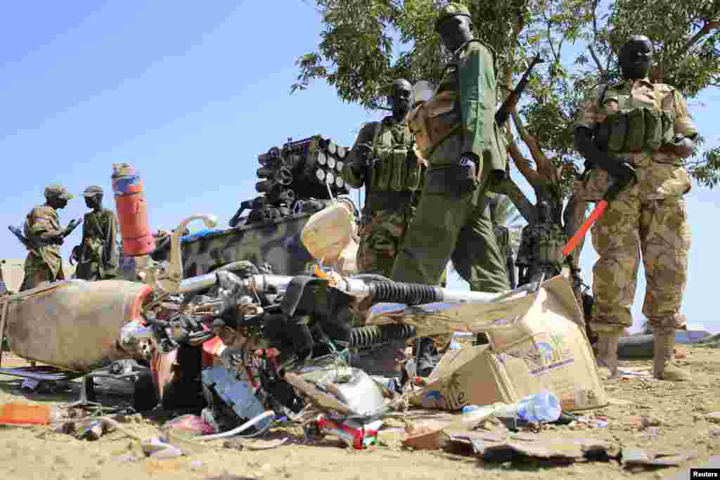 South Sudan army soldiers stand next to a destroyed motorcycle near Bor Airport, Dec. 25, 2013.