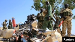 South Sudan army soldiers stand next to a destroyed motorcycle near Bor Airport in Jonglei state, Dec. 25, 2013. 