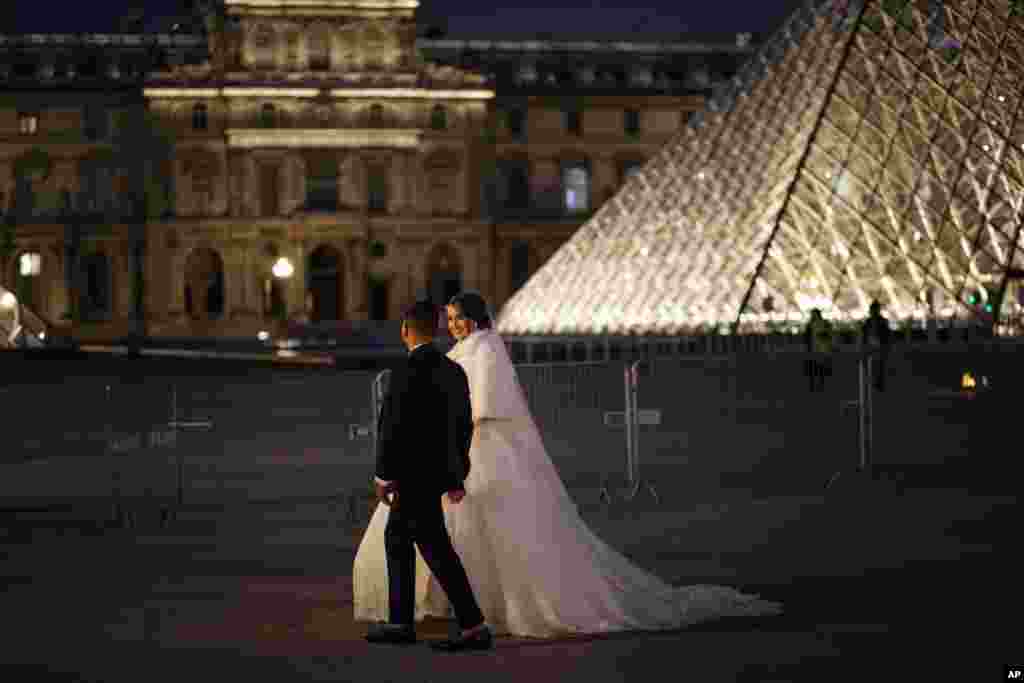 A newly married couple walk by the empty Louvre museum in the center of Paris, Friday, Oct. 30, 2020. France re-imposed a monthlong nationwide lockdown Friday aimed at slowing the spread of the virus, closing all non-essential business and forbidding peop