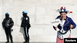 Seorang pria mengenakan kostum berpose di samping polisi di Lincoln Memorial dalam aksi unjuk rasa menentang mandat vaksin di Washington, D.C., pada 23 Januari 2022. (Foto: Reuters/Tom Brenner)