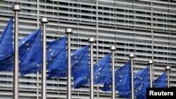 FILE - European Union flags flutter outside EU Commission headquarters in Brussels, Belgium, Oct. 28, 2015.