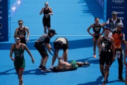 FILE - Mexico's Cecilia Perez, center, collapses after competing in a women's triathlon test event at Odaiba Marine Park, a venue for marathon swimming and triathlon at the Tokyo 2020 Olympics in Tokyo, Aug. 15, 2019.