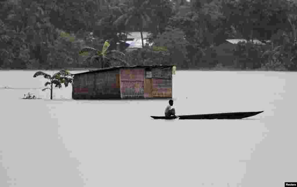 A villager uses a boat to cross flooded areas of Morigaon district in the northeastern Indian state of Assam.