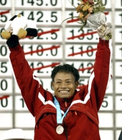 Atlet angkat besi nasional Erwin Abdullah merayakan setelah menerima medali perak dalam upacara penghargaan angkat besi 69 kg, 3 Oktober 2002 di Asian Games ke-14 di Busan. (Foto: AFP/Stephen Shaver)