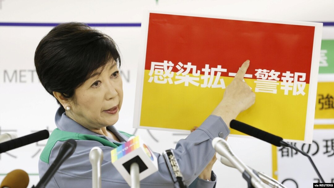 Tokyo Governor Yuriko Koike shows a banner reading 'Infection spread alert' during a news conference on the latest situation of the coronavirus disease (COVID-19) outbreak, in Tokyo, Japan, July 15, 2020, in this photo taken by Kyodo.