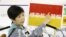 Tokyo Governor Yuriko Koike shows a banner reading 'Infection spread alert' during a news conference on the latest situation of the coronavirus disease (COVID-19) outbreak, in Tokyo, Japan, July 15, 2020, in this photo taken by Kyodo.