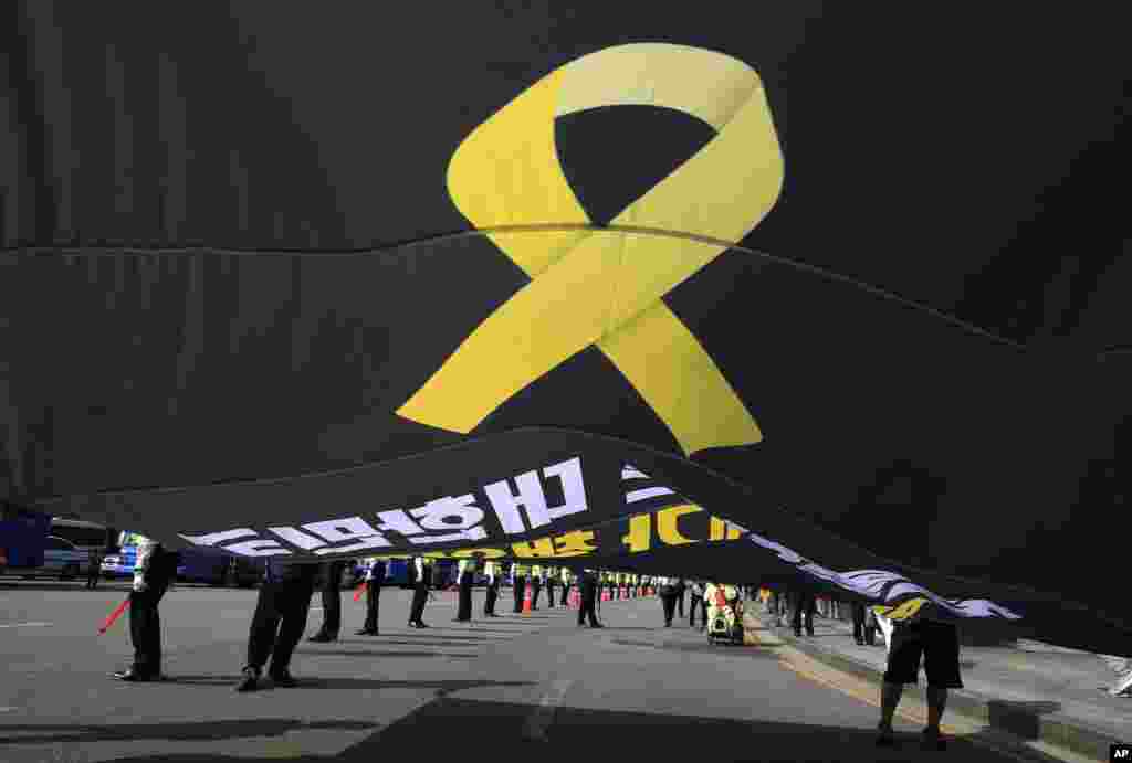 Workers carry a flag depicting a yellow ribbon as a sign of hope for the safe return of missing passengers of the sunken ferry Sewol during a May Day rally to pay tribute to the victims of the accident in Seoul, South Korea, Thursday, May 1, 2014.
