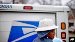 Jamesa Euler, agent de la poste américaine depuis 12 ans, distribue le courrier sous la pluie dans le quartier de Cabbagetown, 7 février 2013, à Atlanta. (AP Photo / David Goldman)