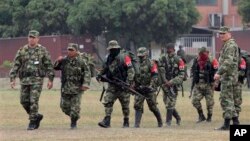 Tentara Kolombia (kanan dan kiri) mengawal para pemberontak dari Laskar Pembebasan Nasional (ELN) saat menyerahkan diri di basis militer di Cali, Kolombia, 16 Juli 2013 (Foto: dok).