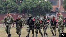 FILE - Soldiers, left and right, escort rebels of the National Liberation Army who gave themselves up upon arrival at a military base in Cali, Colombia, July 16, 2013.