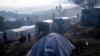 Des migrants se tiennent devant leurs tentes de fortune à l'extérieur du périmètre du camp de réfugiés surpeuplé de Moria sur l'île de Lesbos, en Grèce, le 28 janvier 2020. 