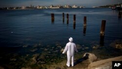 Un hombre vestido de blanco realiza un ritual de santería frente a la bahía de La Habana.