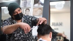 Seorang tukang cukur memotong rambut kliennya di sebuah salon di London utara, 12 April 2021. (Foto: DANIEL LEAL-OLIVAS / AFP)