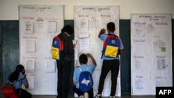 Estudiantes revisan un tablero informativo en el marco del programa de regreso a clases progresivo luego de ser vacunados contra la enfermedad del nuevo coronavirus, COVID-19, en el centro educativo Andrés Bello en Caracas el 9 de noviembre de 2021.