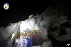 In this photo released early Monday, Oct. 17, 2016 and provided by the Syrian Civil Defense group known as the White Helmets, rescue workers try to remove a boy stuck in the debris of a building in the neighborhood of Qaterji in rebel-held east Aleppo.