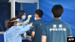 Des agents de santé prélèvent des échantillons d'agents de police sud-coréens pour le test du coronavirus à Séoul, le 19 août 2020. (Photo by Jung Yeon-je / AFP)