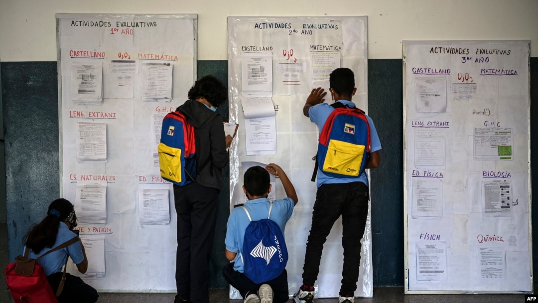 Estudiantes revisan un tablero informativo en el marco del programa de regreso a clases progresivo luego de ser vacunados contra la enfermedad del nuevo coronavirus, COVID-19, en el centro educativo Andrés Bello en Caracas el 9 de noviembre de 2021.