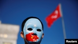 FILE - An ethnic Uighur boy wears a mask during a protest against China in Istanbul, Turkey, Dec. 14, 2019. 