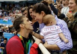 FILE - In this Aug. 9, 2016, photo, United States' swimmer Michael Phelps celebrates winning his gold medal in the men's 200-meter butterfly with his fiance Nicole Johnson and baby, Boomer, during the 2016 Games.