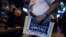 Mideast Israel 2016 US Election: An Israeli man holds a sign of U.S. presidential candidate Republican Donald Trump as he watches a live update with friends of the U.S. presidential election results at Mike's place bar in Jerusalem, Wednesday Nov. 9, 2016