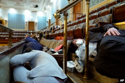 People shelter in the House gallery as protesters try to break into the House Chamber at the U.S. Capitol on Wednesday, Jan. 6, 2021, in Washington. (AP Photo/Andrew Harnik)