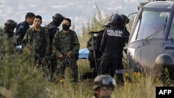 Vojnici čuvaju stražu dok meksička federalna policija nosi telo jedne od žrtava nesreće helikoptera u kojoj je poginuo i ministar unutrašnjih poslova Fransisco Blejk Mora