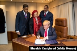 President Donald J. Trump, with Alveda King, center, niece of slain Civil Rights leader Dr. Martin Luther King Jr., and joined by Isaac Newton Farris Jr., left, nephew of Dr. King, and Bruce Levell of the National Diversity Coalition for Trump, right, signs the Martin Luther King Jr. National Historical Park Act, Jan. 8, 2018, aboard Air Force One, in Atlanta, Ga.