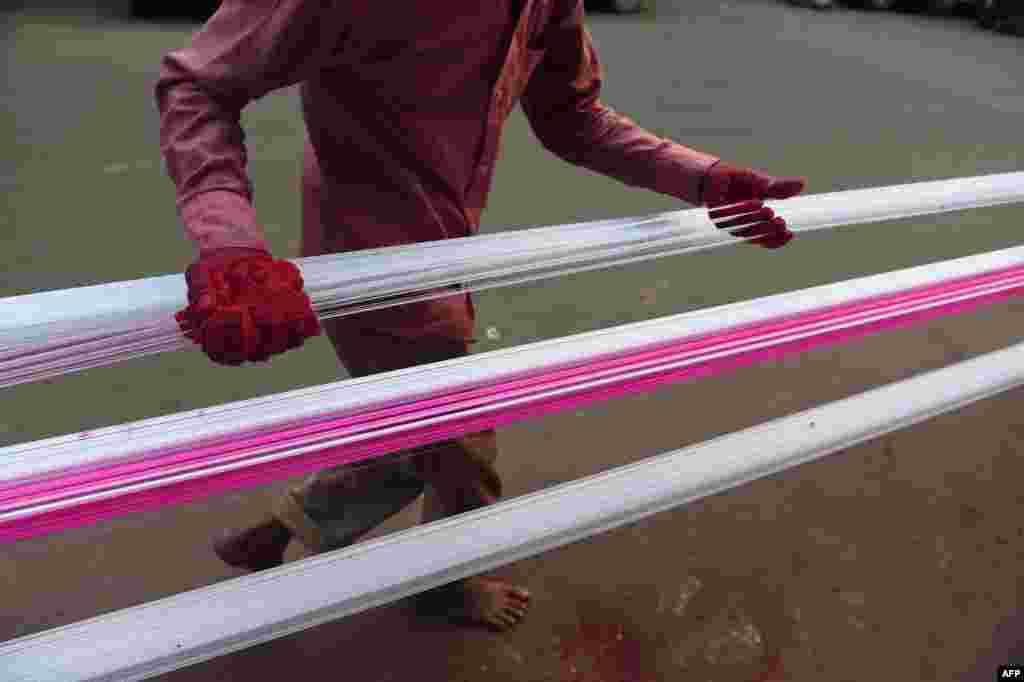 A man coats strings for flying kites with colored glass powder ahead of 'Uttarayan' or Kite festival, in Ahmedabad, India.