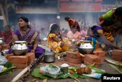 A girl covers her eyes from smoke as devotees prepare ritual rice dishes to offer to the Hindu Sun God as they attend Pongal celebrations at a slum in Mumbai January 14, 2014. Pongal is a harvest festival celebrated by Tamils across the country. REUTERS/D