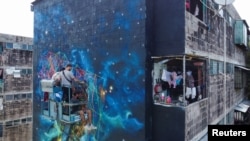 A drone view shows members of the Fullpaint 360 collective installing cords in a mural titled "Constelacion de Zacamil" by Italian artist Adriano Lombardo in Mejicanos, El Salvador, July 30, 2024.