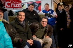 Former Texas Gov. Rick Perry, center, bites his lip as he gets up to introduce Republican presidential candidate, Sen. Ted Cruz, R-Texas, left, at a campaign event at High Point Bulls Oswald Barn in Osceola, Iowa, Jan. 26, 2016.