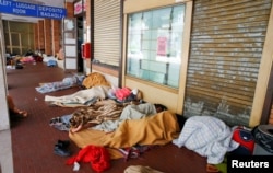 Migrants sleep under blankets in a makeshift camp at the San Giovanni railway station in Como, Italy, Aug. 12, 2016.
