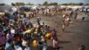 FILE - Displaced people gather around a water truck to fill containers at a United Nations compound that has become home to thousands of people displaced by the recent fighting, in the capital Juba, South Sudan. 