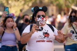 FILE - Guests walk along Main Street USA at Disneyland in Anaheim, Calif., April 30, 2021. Los Angeles and San Francisco have reopened more businesses under California's least restrictive coronavirus safety rules.