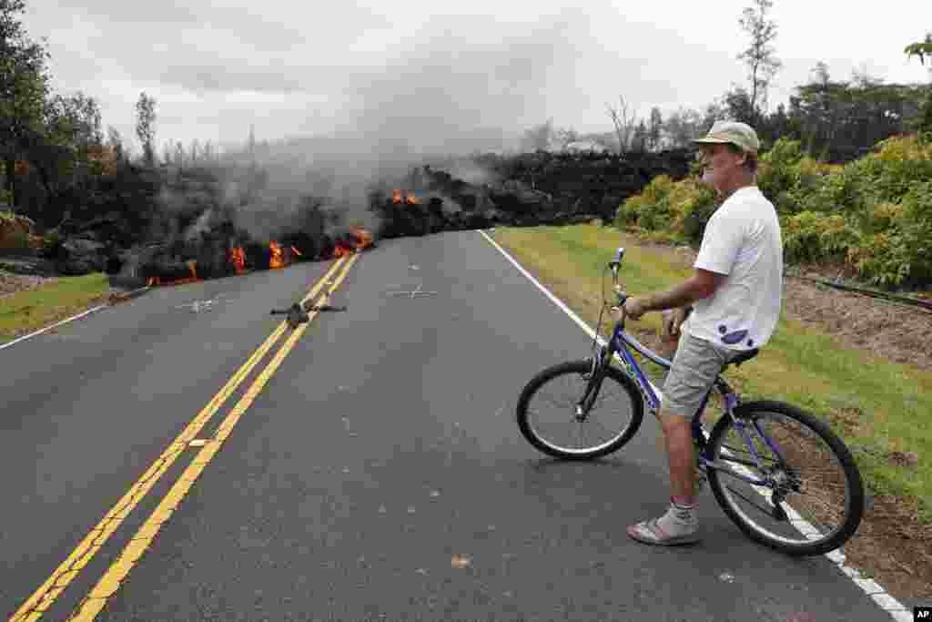 Hawaii resident Sam Knox watches the lava stretch across the road, Saturday, May 5, 2018, in Pahoa, Hawaii. Knox&#39;s home is less than a few hundred meters from the lava flow and he does not have any plans to evacuate. Knox is hopeful the lava will not destroy his home.