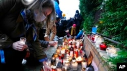 FILE - Warsaw residents place candles in front of the national Border Guards Headquarters in Warsaw, Poland, as a sign of mourning for four migrants found dead over the weekend along the border between Poland and Belarus, Sept. 20, 2021.