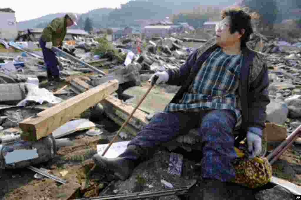 A woman looks out over the destroyed landscape in Ofunato City, Iwate Prefecture in northern Japan, after an earthquake and tsunami struck the area, March 13, 2011.