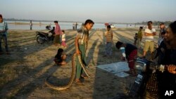 FILE - A snake charmer walks with pythons on his shoulder to attract tourists in Amarapura, Mandalay region, Myanmar, Jan. 2, 2016. Mandalay alone registers an estimated 700 to 800 snake bite victims each year.