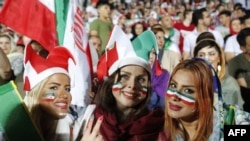 FILE -- Iranian women cheer as they wave their country's flag after authorities in a rare move allowed a select female group into Tehran's Azadi Stadium to watch a friendly soccer match between Iran and Bolivia, Oct. 16, 2018. 