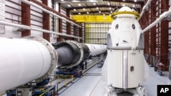 In this Dec. 18, 2018 photo provided by SpaceX, SpaceX's Crew Dragon spacecraft and Falcon 9 rocket are positioned inside the company's hangar at Launch Complex 39A at NASA's Kennedy Space Center in Florida. (Space X via AP)