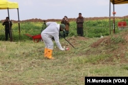 Workers identify places to begin the search for the remains of Yazidi victims in Kocho, Iraq, March 15, 2019.