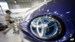 A worker walks past a Toyota car at a Toyota showroom in Tokyo, Wednesday, June 29, 2016. 