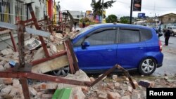A car covered by debris is seen near a collapsed wall following an earthquake in Quetzaltenango, Guatemala, June 14, 2017. 