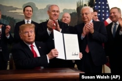 President Donald Trump holds up a signed proclamation recognizing Israel's sovereignty over the Golan Heights, as Israeli Prime Minister Benjamin Netanyahu looks on in the Diplomatic Reception Room of the White House in Washington, Monday, March 25, 2019.